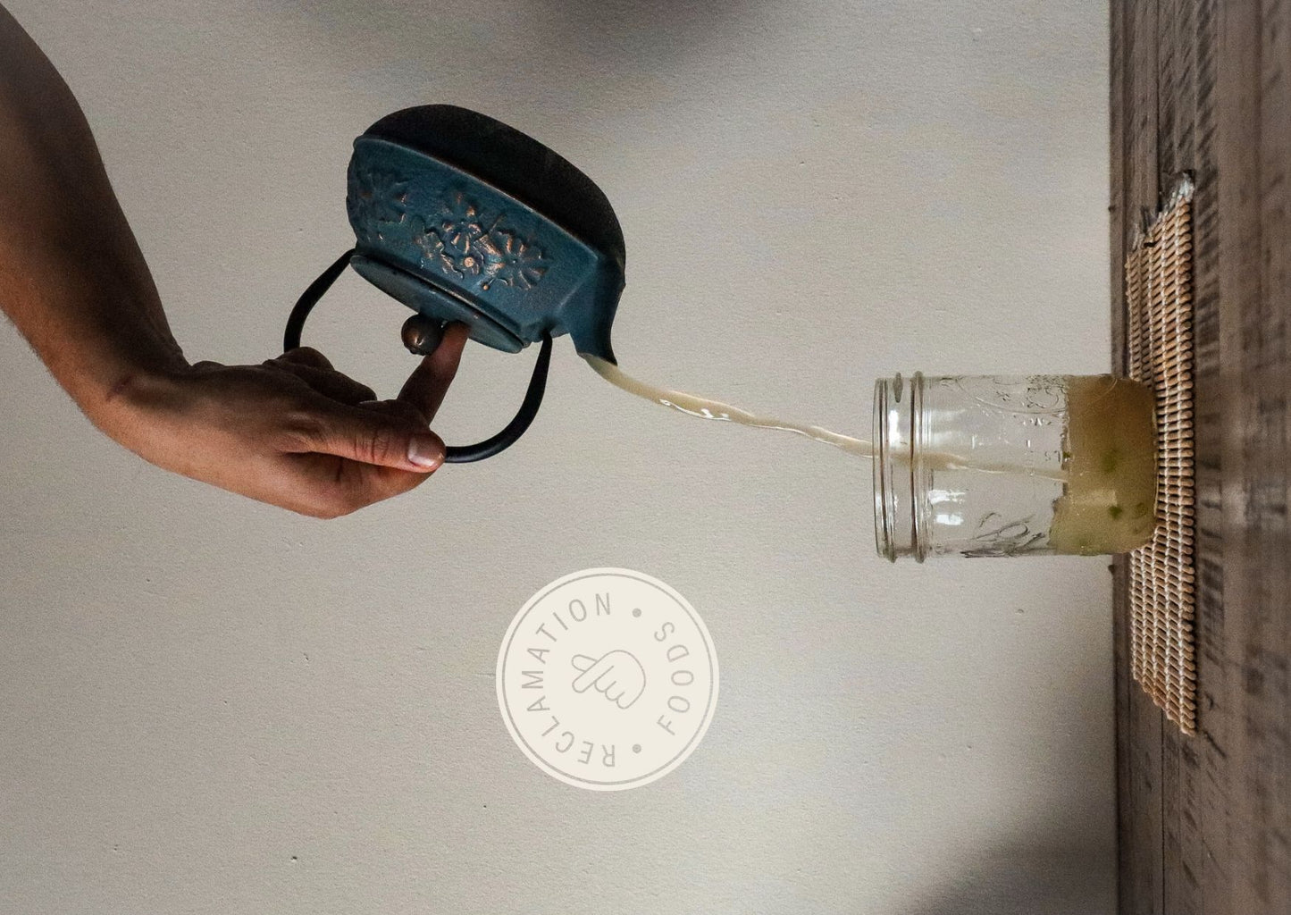 Pouring broth from a tea kettle into a jar with sliced scallions
