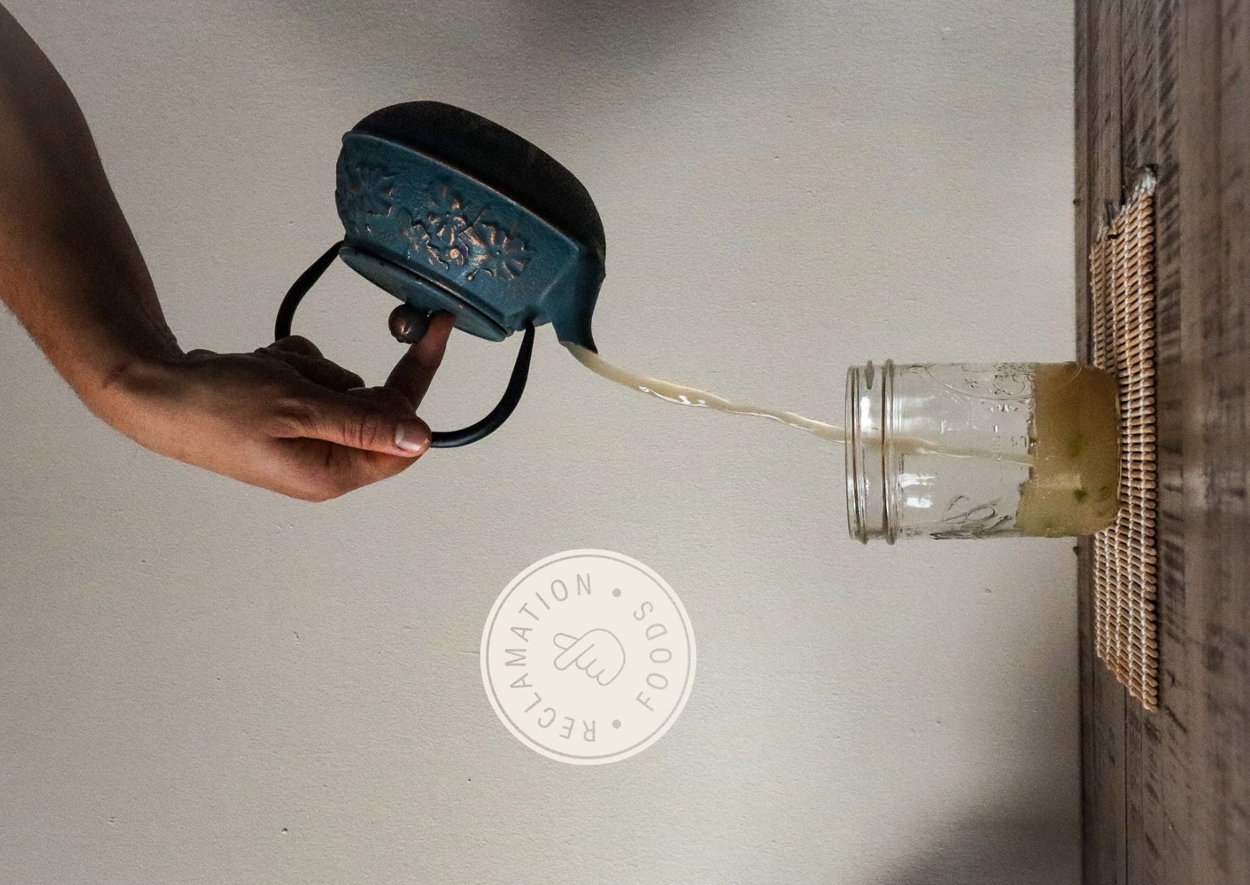 Pouring broth from a tea kettle into a jar with sliced scallions