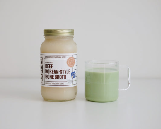 A jar of Reclamation Foods Korean-style bone broth beside a cup of matcha latte made with broth