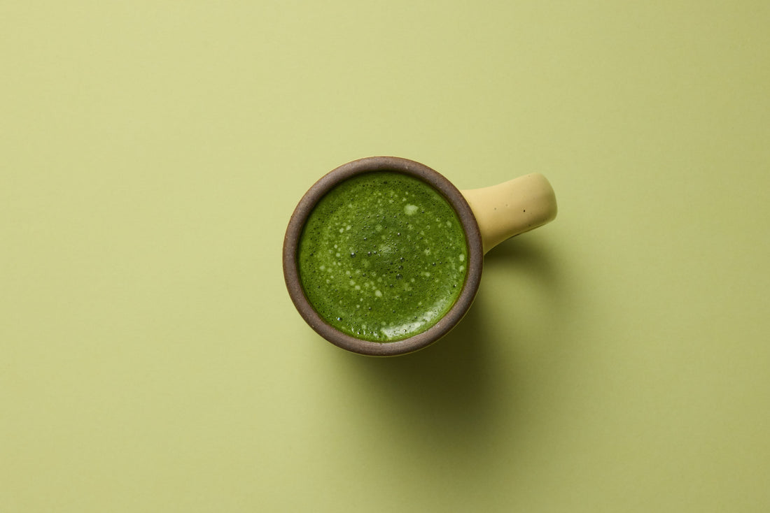 Overhead view of bone broth matcha latte in a yellow mug.