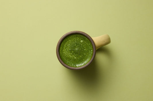 Overhead view of bone broth matcha latte in a yellow mug.