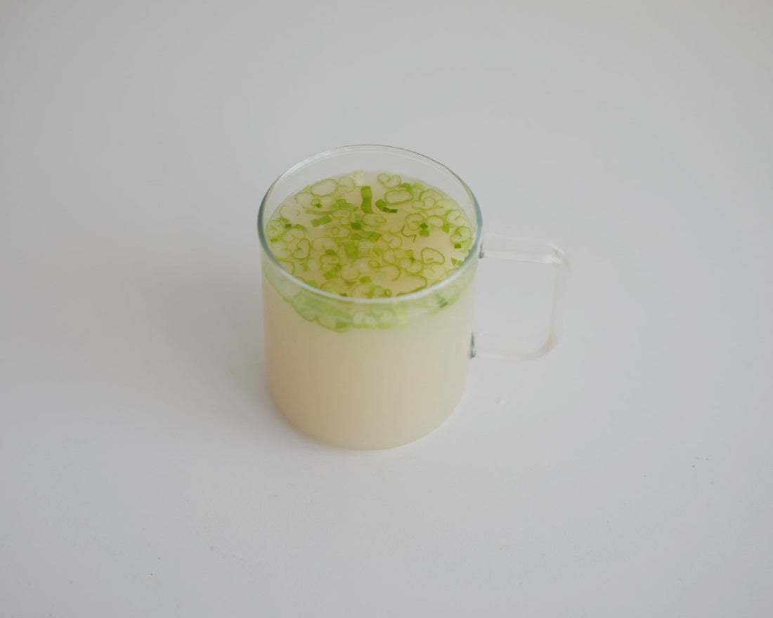 A cup of Korean-style bone broth topped with scallions
